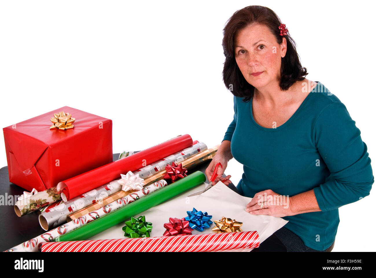 Una donna di mezza età impacchettare i regali di Natale su uno sfondo bianco. Foto Stock