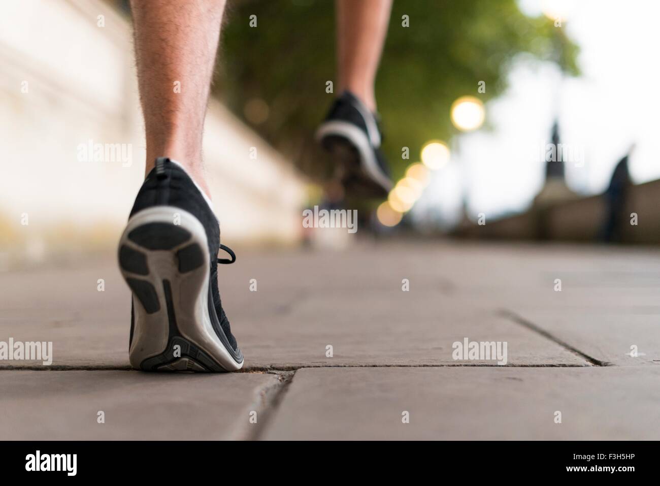 Giovane maschio corridori indossando dei formatori in esecuzione sul marciapiede Foto Stock