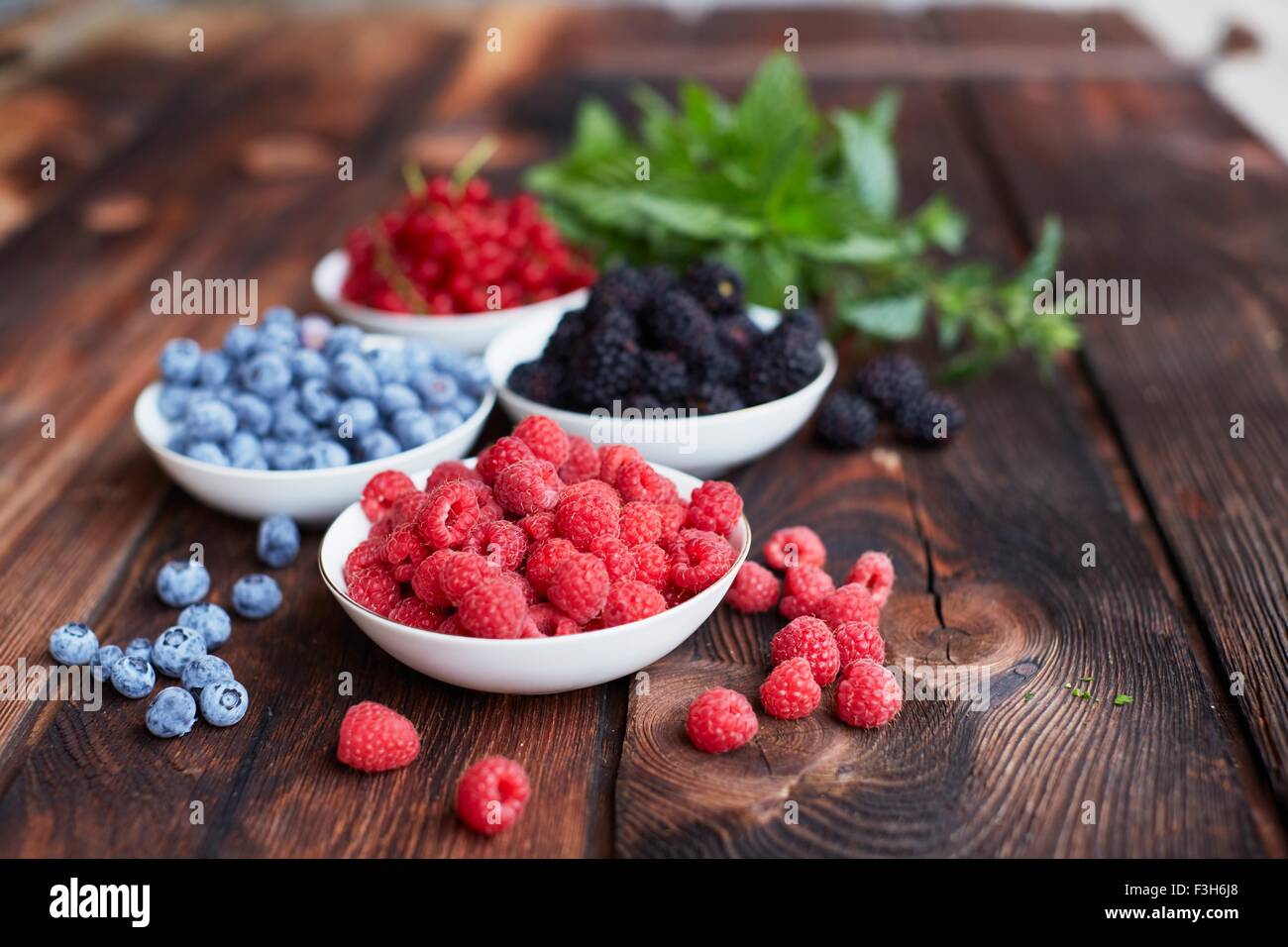 Tavolo da picnic con quattro coppe di frutti di bosco freschi Foto Stock