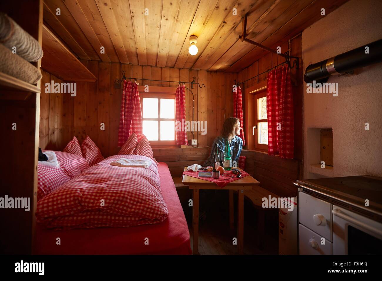 Giovane donna guardando fuori della finestra di capanna, Val Senales Alto Adige - Italia Foto Stock