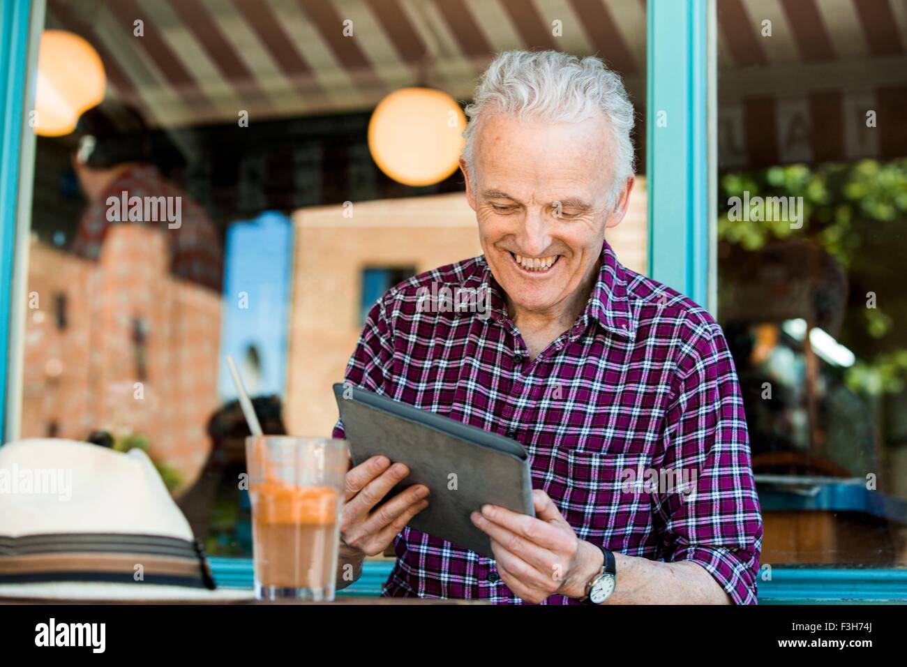 Senior uomo con tavoletta digitale presso il cafe Foto Stock