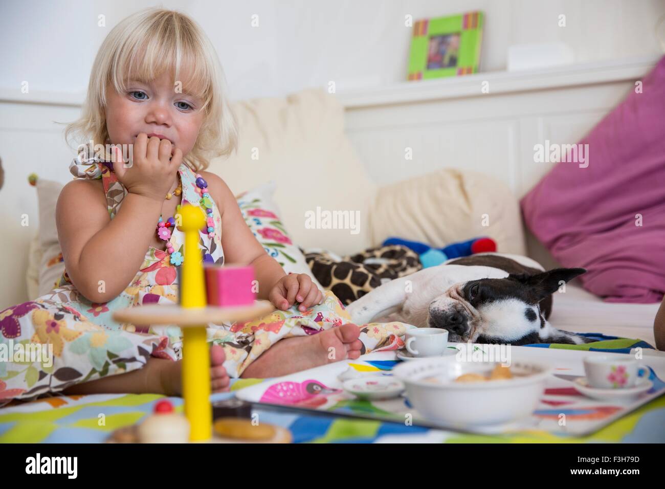 Toddler femmina giocando con il giocattolo set da tè sul letto Foto Stock Toddler femmina giocando con il giocattolo set da tè sul letto Foto Stock