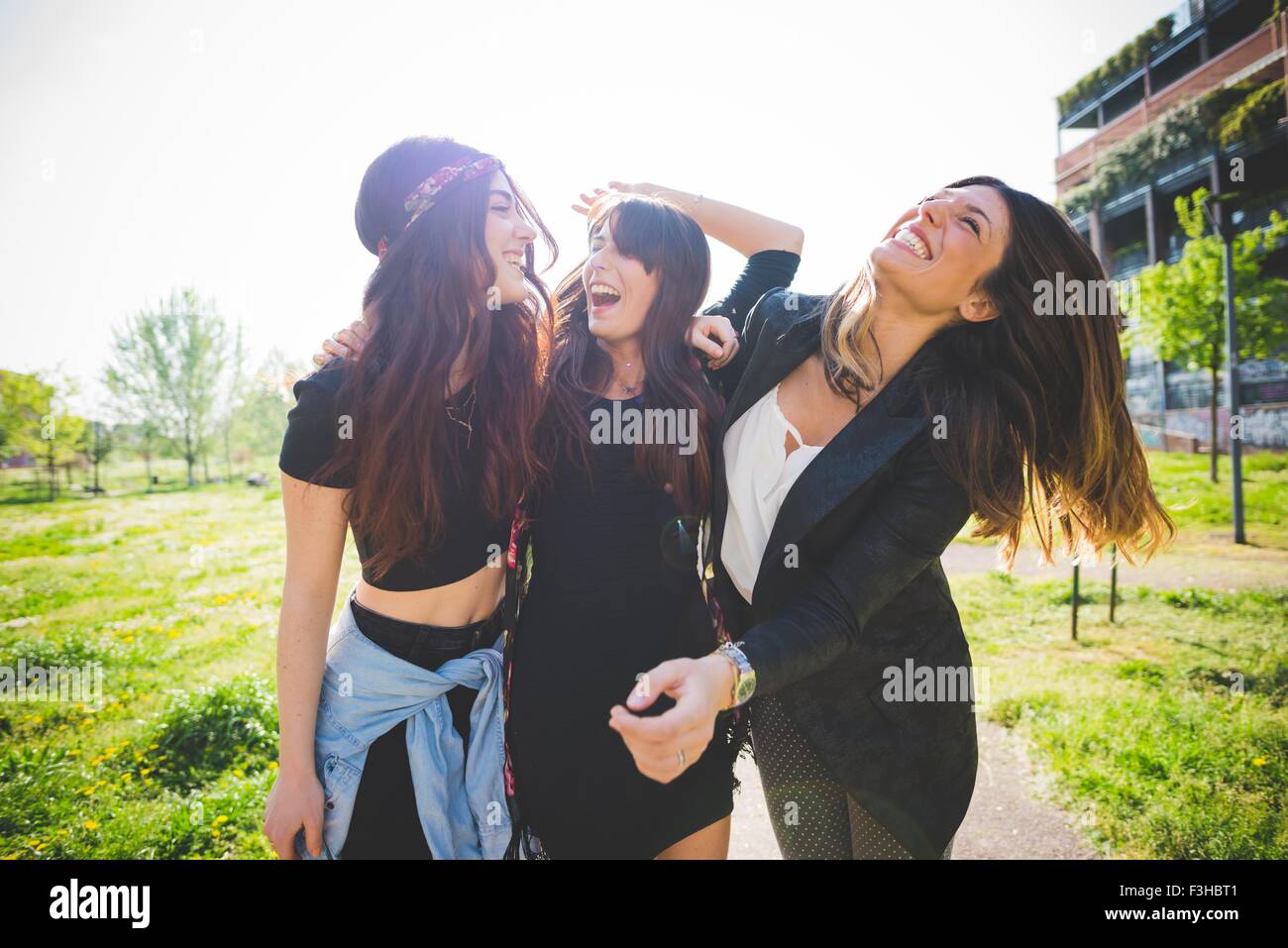 Tre giovani amici di sesso femminile ridere insieme in posizione di parcheggio Foto Stock