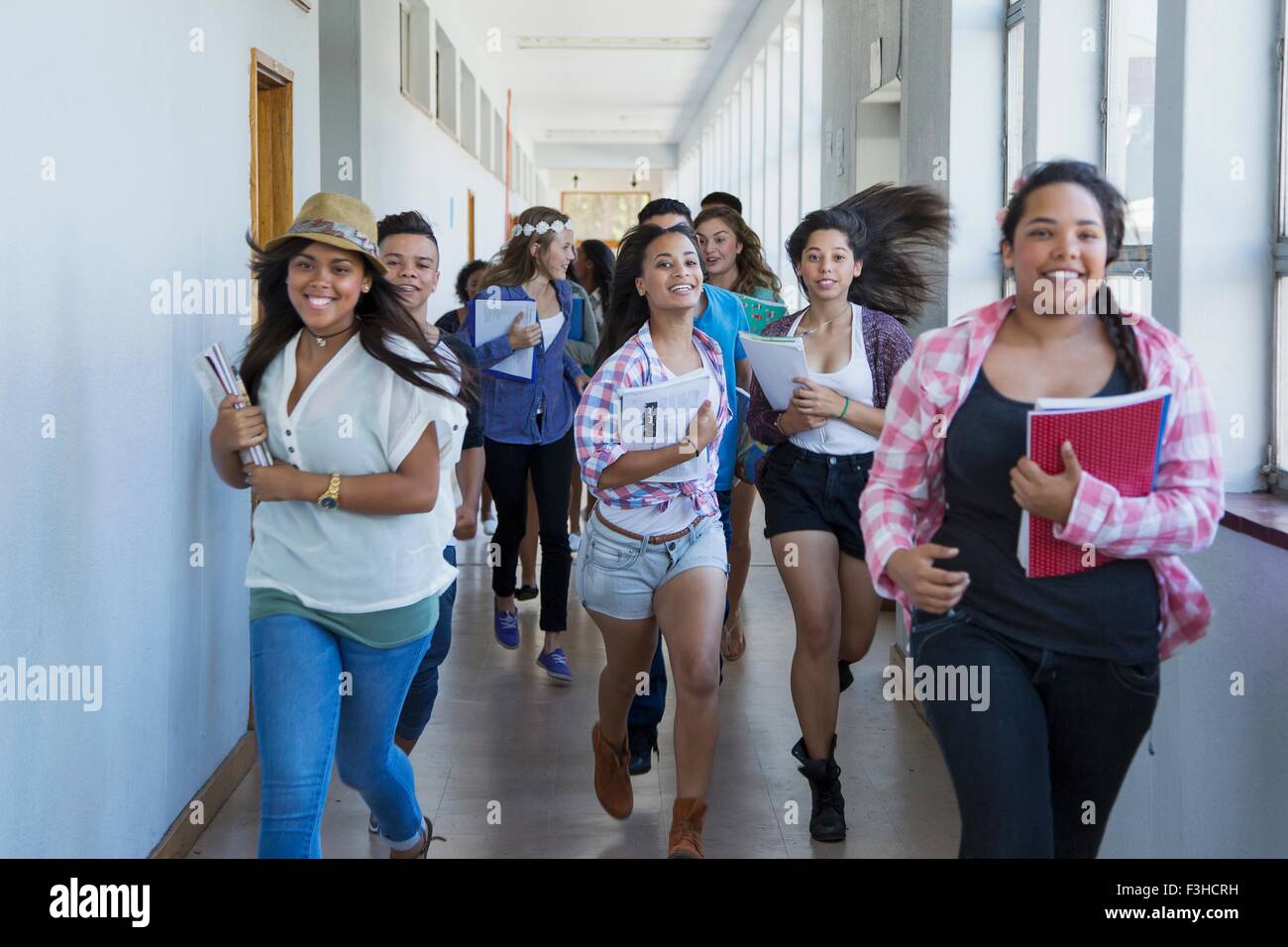 Gli studenti che corre lungo il corridoio, ridendo Foto Stock