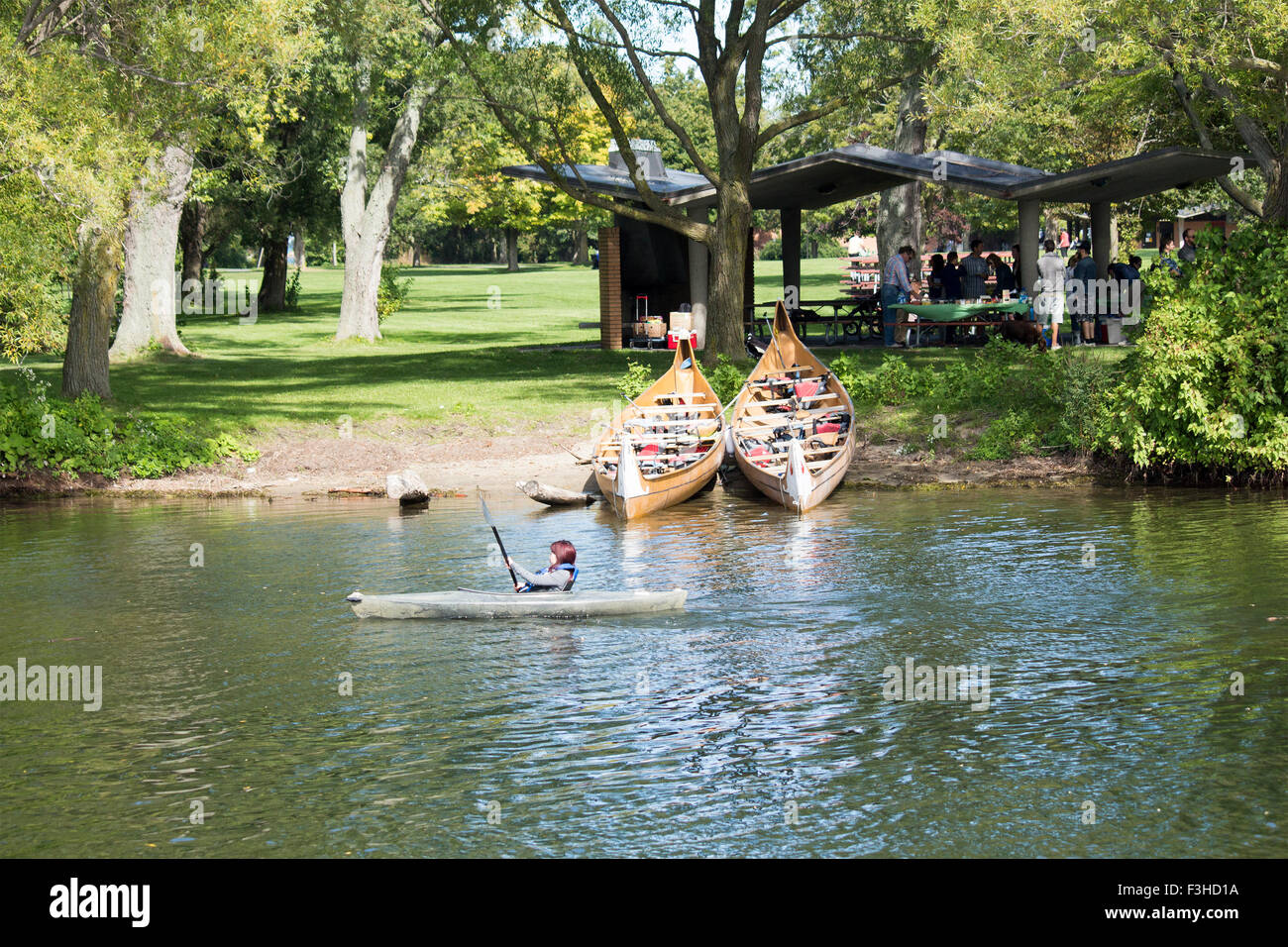 Ragazza adolescente in kayak sul lago Ontario righe passato due canoe e le persone aventi un barbeque sul centro isola a Toronto, Ontario, Canada Foto Stock