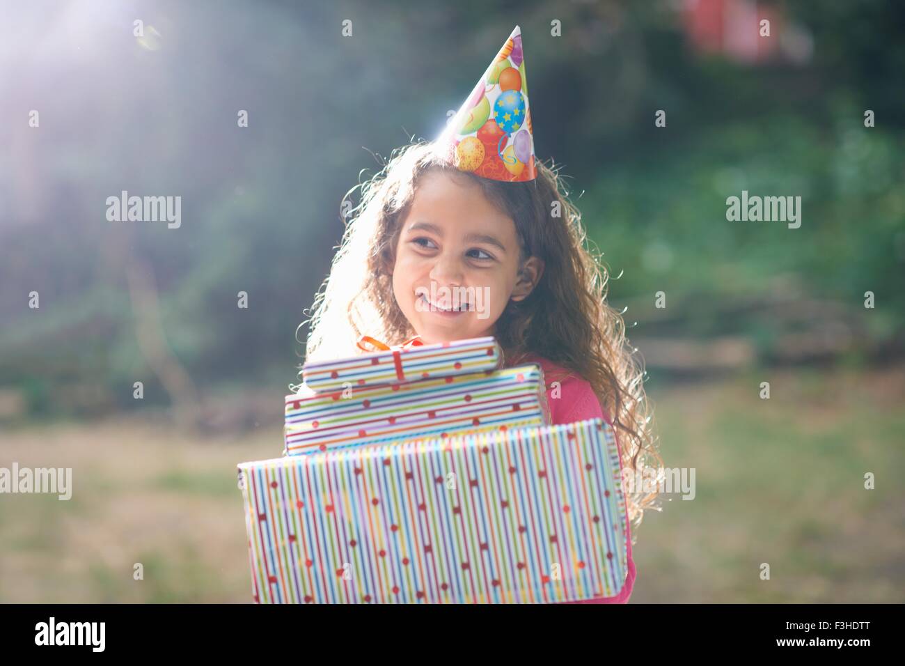 La ragazza che porta pila di doni al giardino festa di compleanno Foto Stock