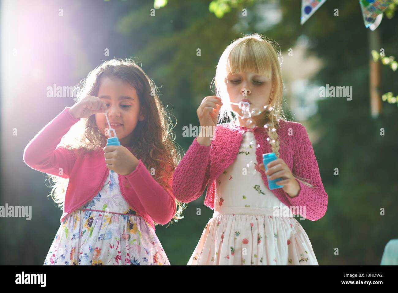 Due cute ragazze soffiare bolle in giardino Foto Stock