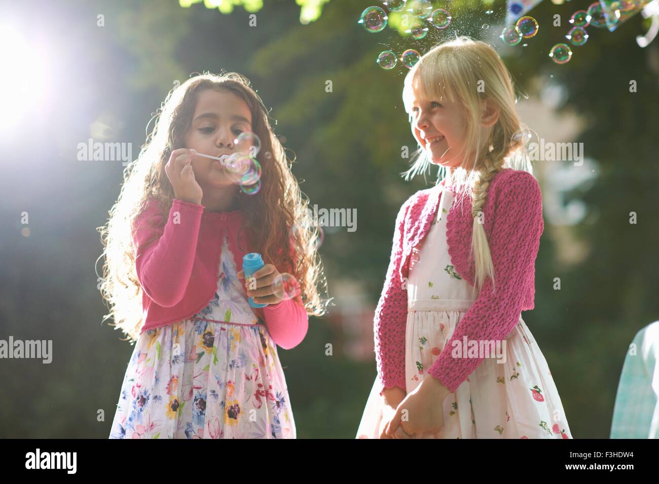 Due cute ragazze soffiare bolle nel giardino soleggiato Foto Stock