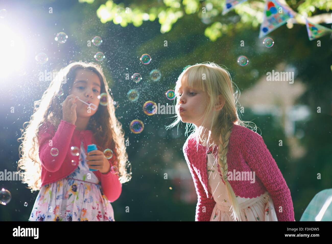 Due ragazze a soffiare bolle nel giardino soleggiato Foto Stock