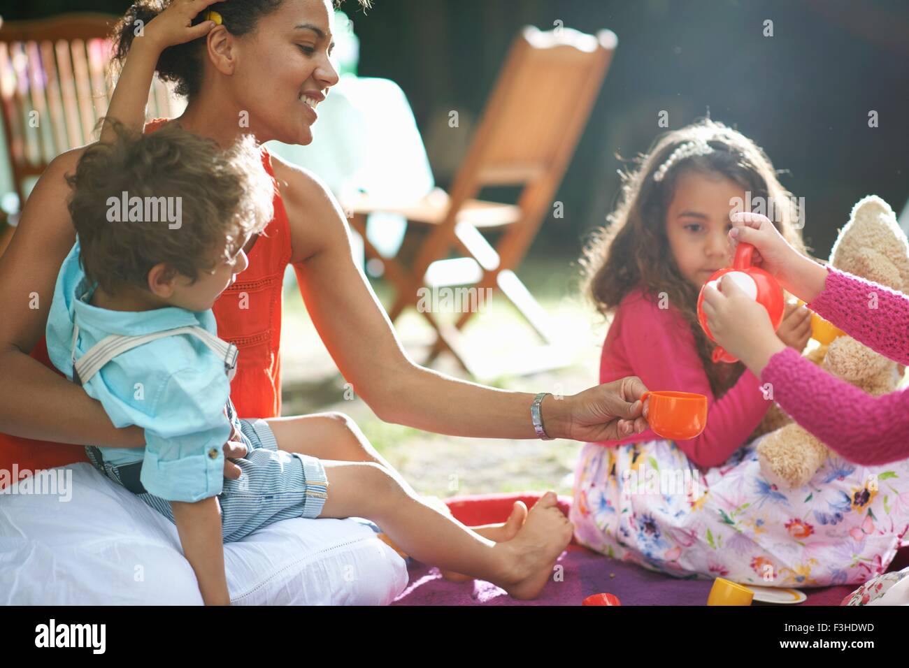 Madre e bambini che giocano un pic-nic in giardino festa di compleanno Foto Stock
