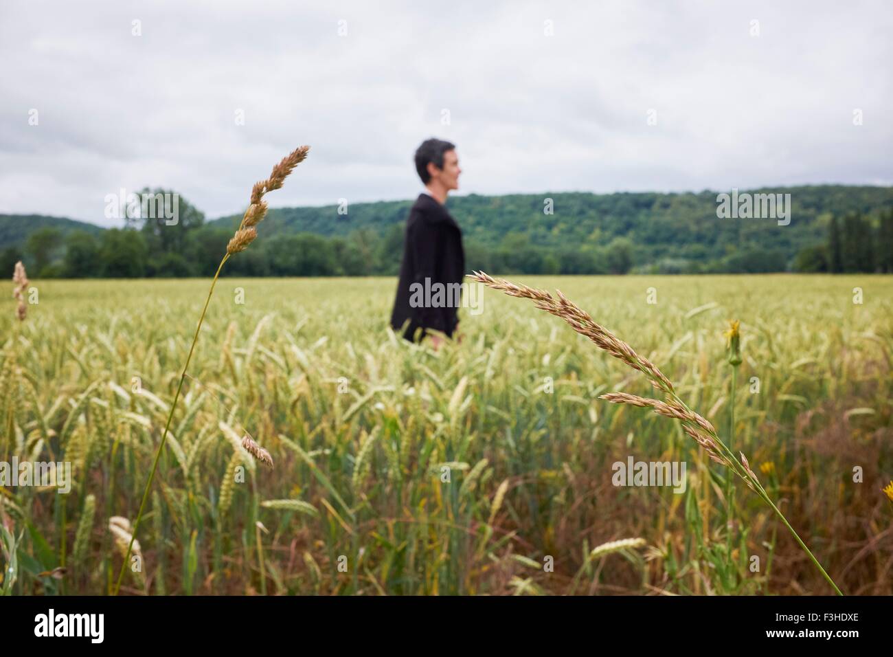 Vista laterale della donna in piedi in cornfield Foto Stock