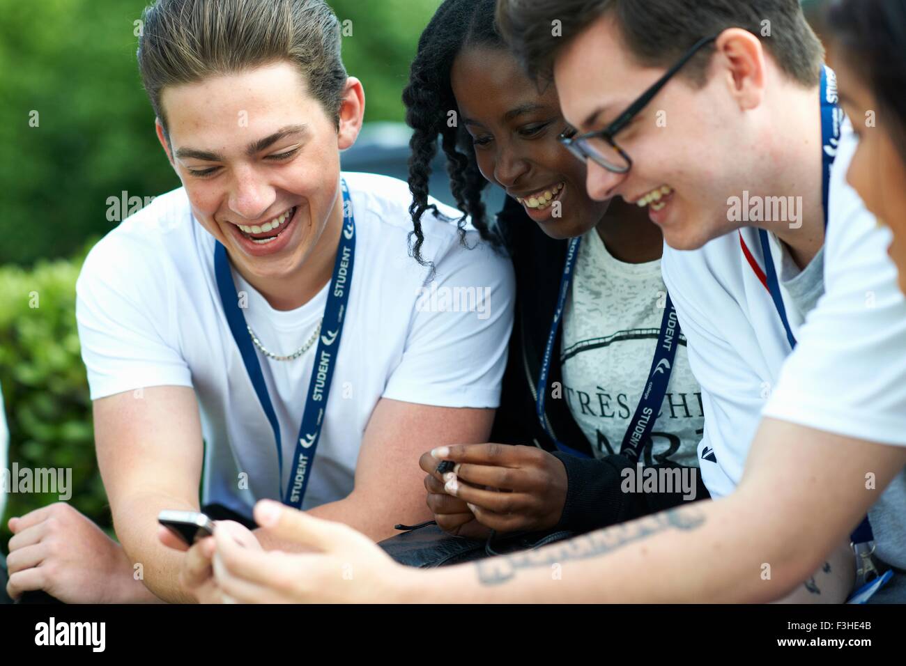 Studenti e studentesse su college campus lettura messaggio sullo smartphone Foto Stock