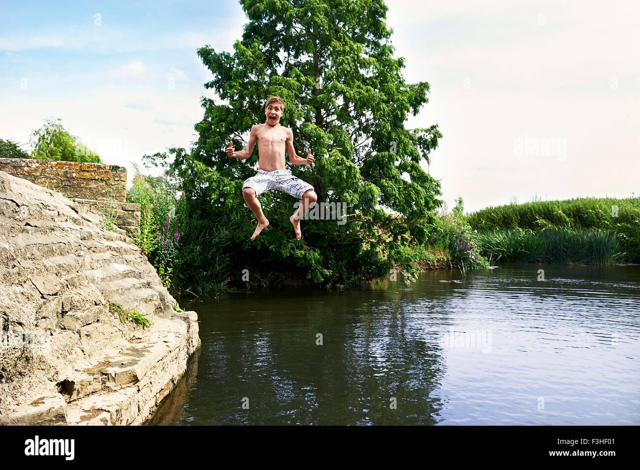 Ragazzo adolescente jumping metà aria nel lago Foto Stock
