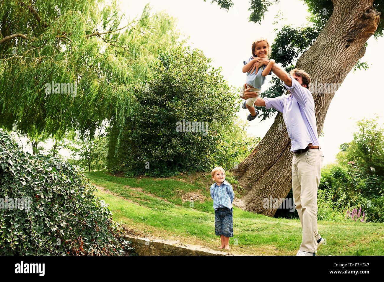 Uomo maturo sollevando la figlia in giardino Foto Stock