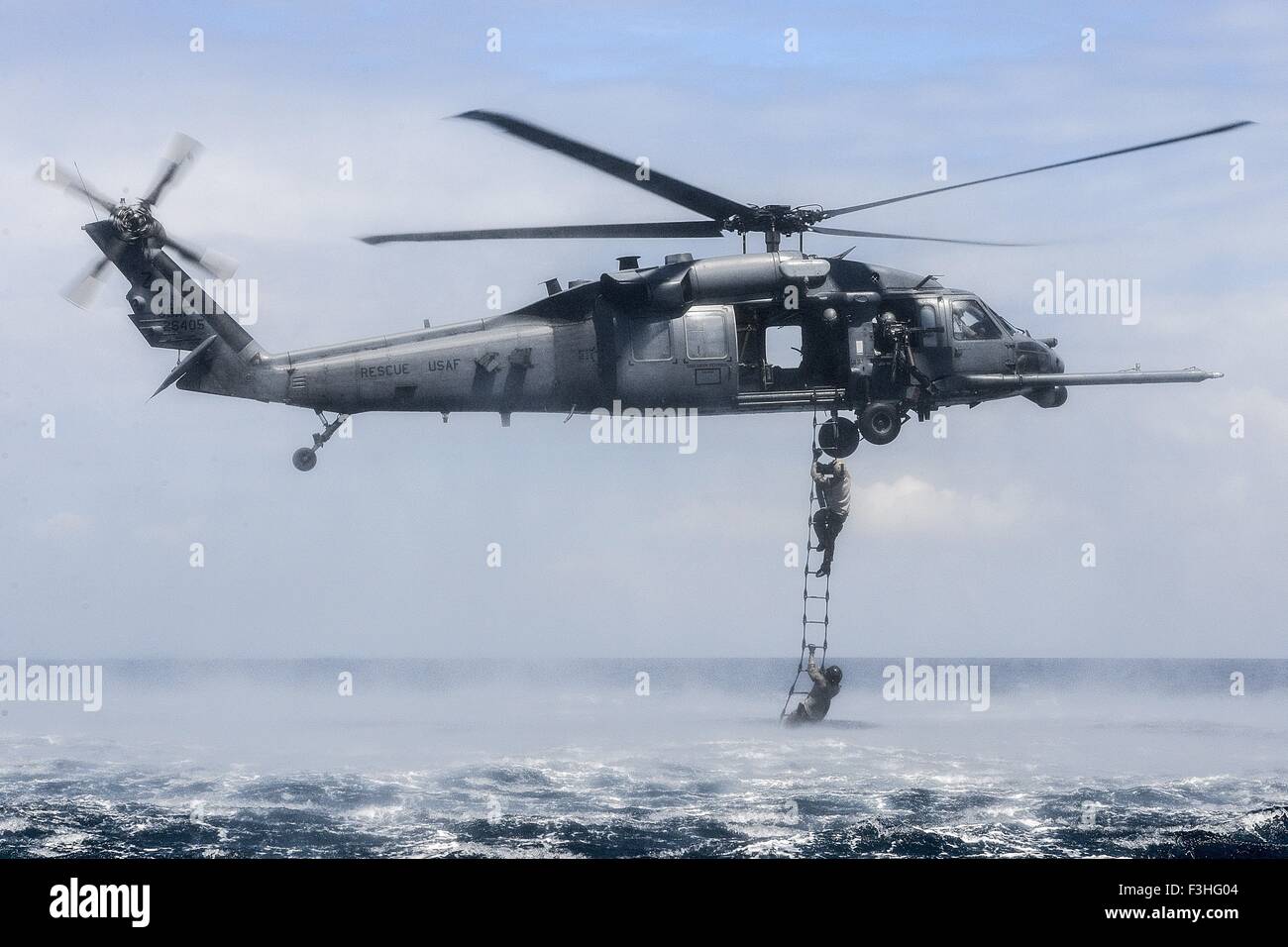Stati Uniti Air Force delle forze speciali rescue commandos saltare da un HH-60G Pave Hawk elicottero nell'oceano durante la formazione anfibio chiamato helo-casting Ottobre 7, 2015 a Okinawa, Giappone. 320STS aviatori di eseguire la formazione anfibio Foto Stock