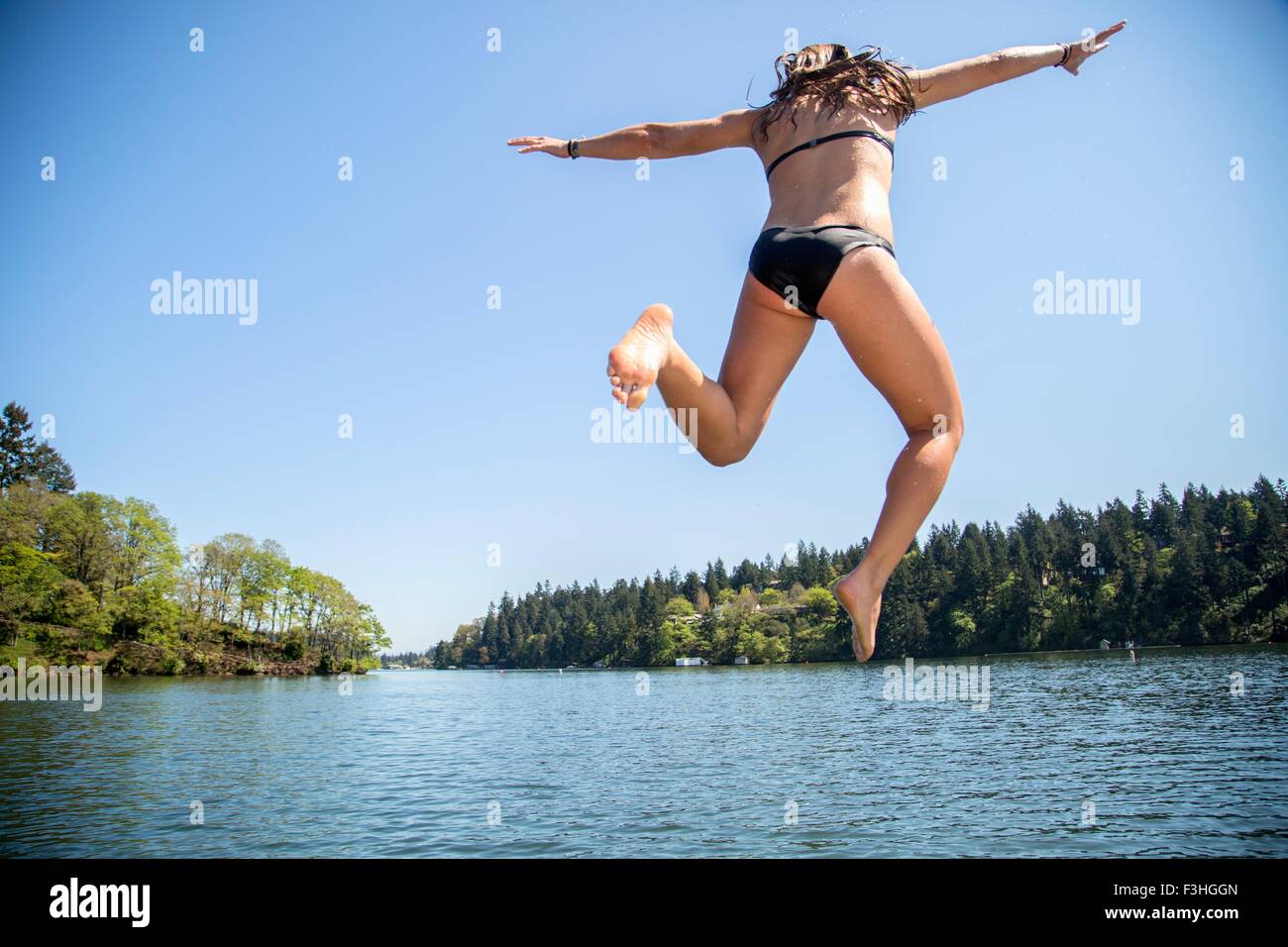 Vista posteriore della giovane donna il salto in Lake Oswego, Oregon, Stati Uniti d'America Foto Stock