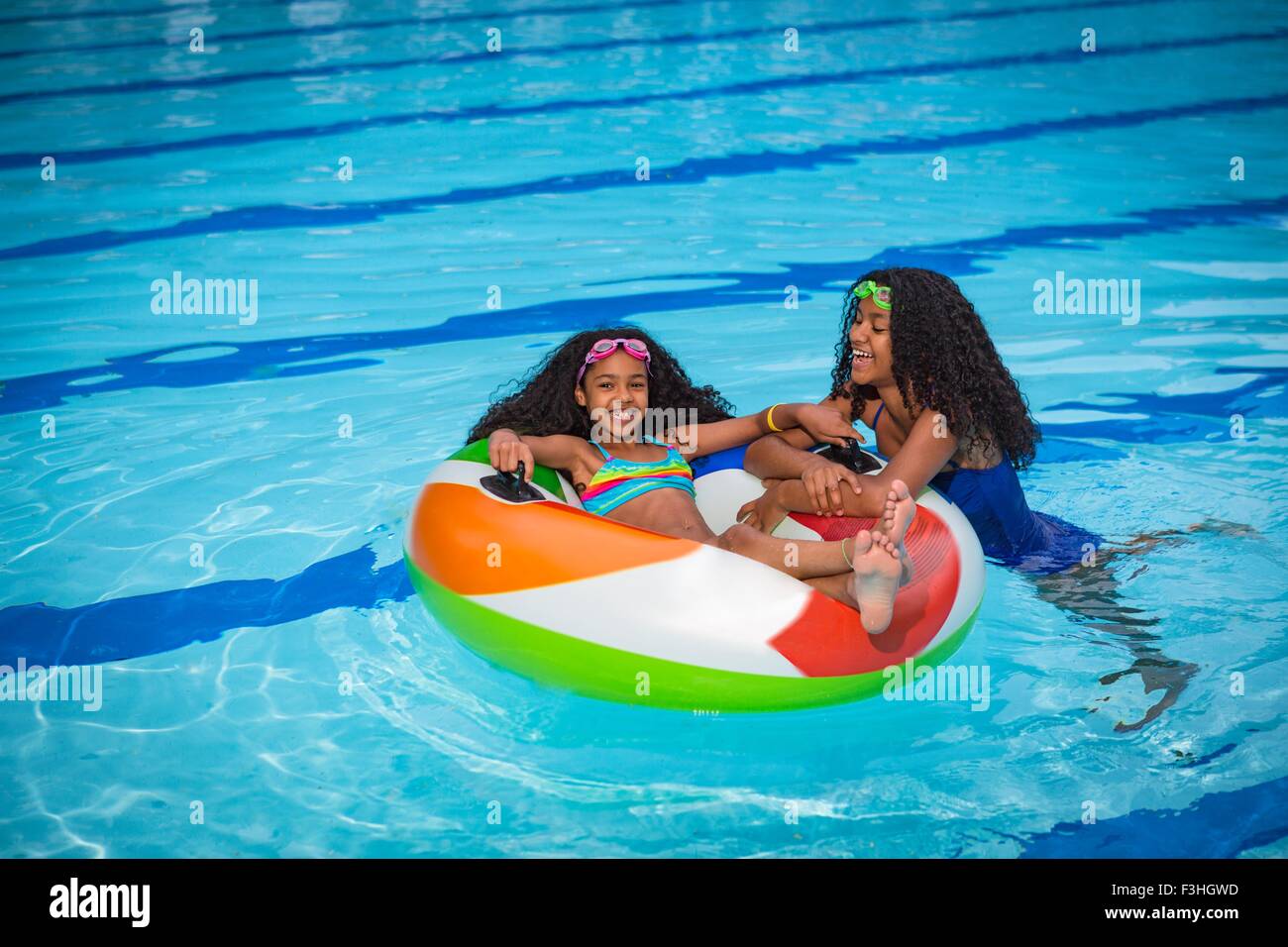 Ragazze in piscina a giocare con anello gonfiabile, sorridente Foto Stock
