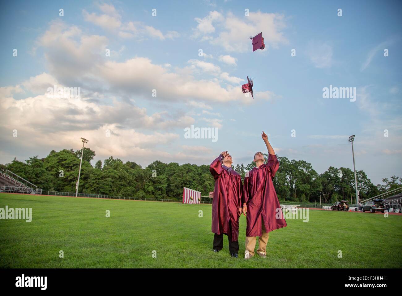 I laureati nel lanciare fino cappelli a metà in aria Foto stock - Alamy