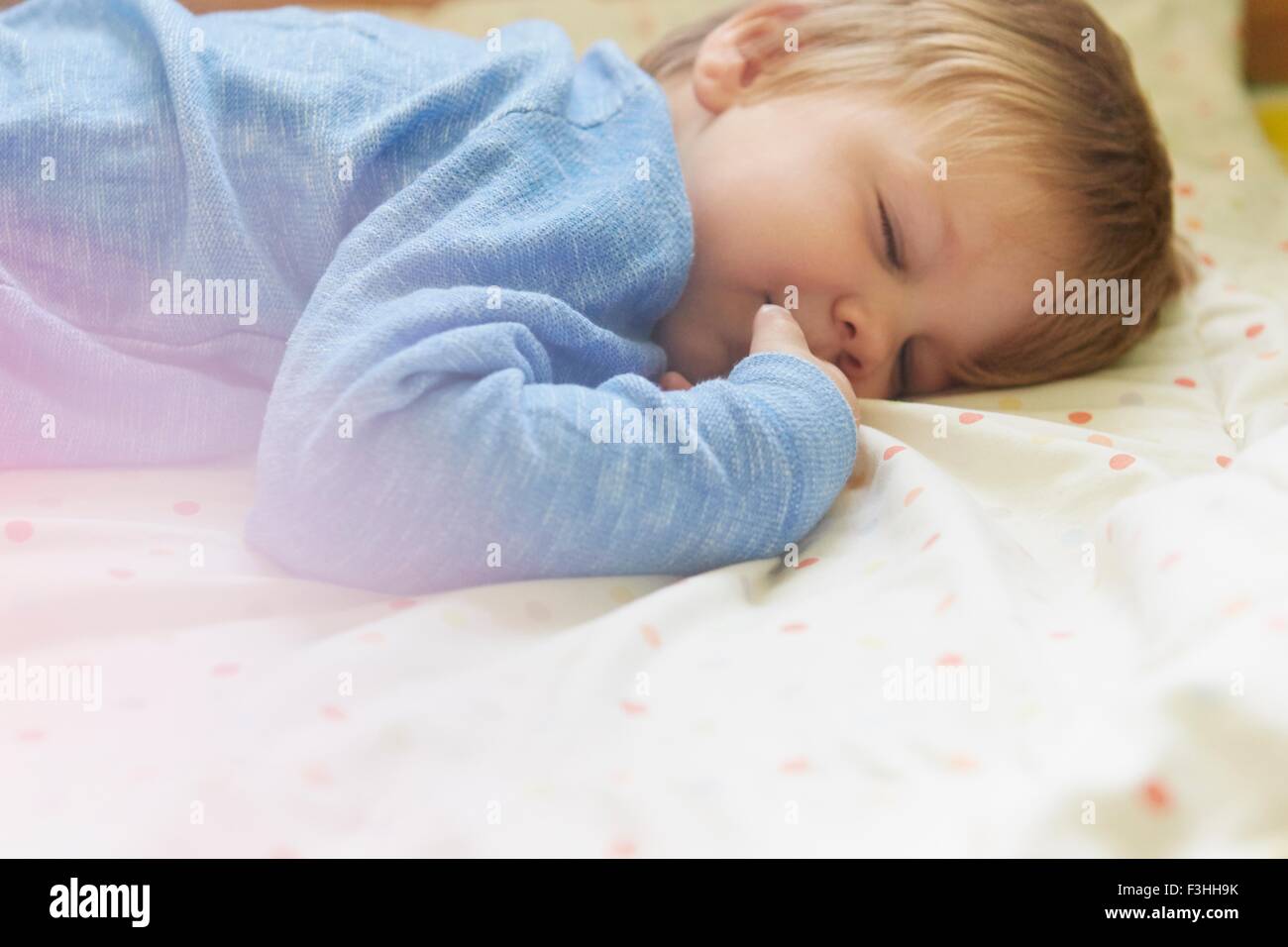 Sleeping boy giacente sulla parte anteriore a letto, vista laterale, vita fino Foto Stock