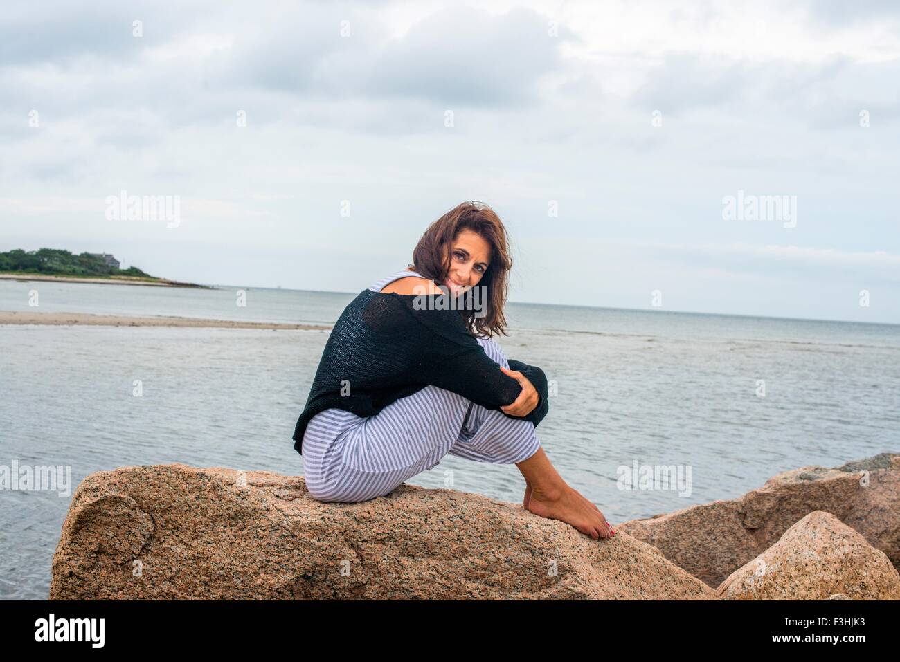 Ritratto di donna matura seduta sulle rocce costiere, Foto Stock