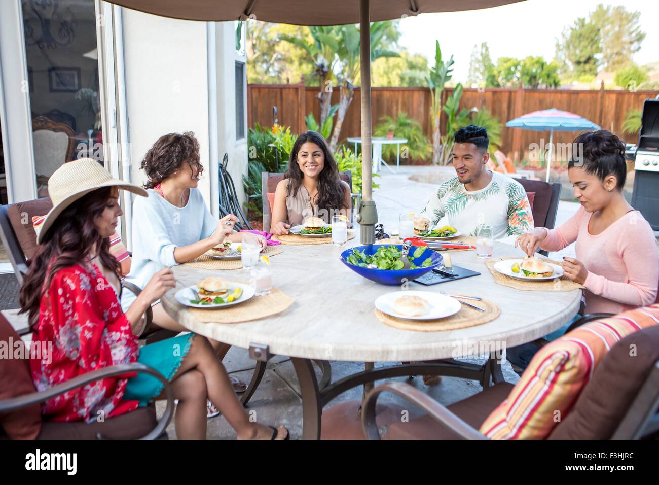 Giovane uomo e quattro sorelle adulte aventi famiglia pranzo a barbecue sul patio Foto Stock