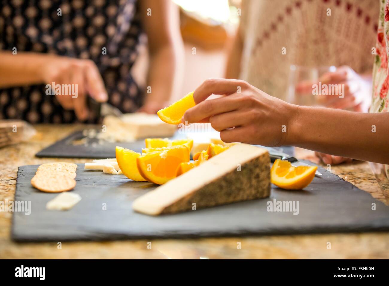 Close up di tre sorelle adulte snacking dalla scheda di formaggio Foto Stock