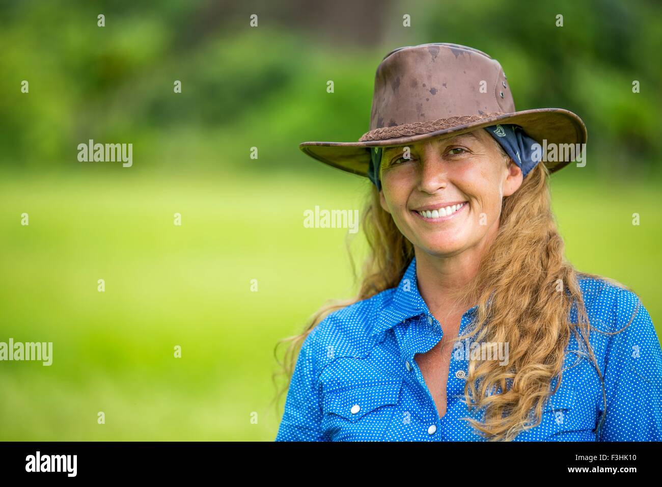 Ritratto di donna matura, in piedi in campo, indossando il denim camicia e cappello da cowboy Foto Stock