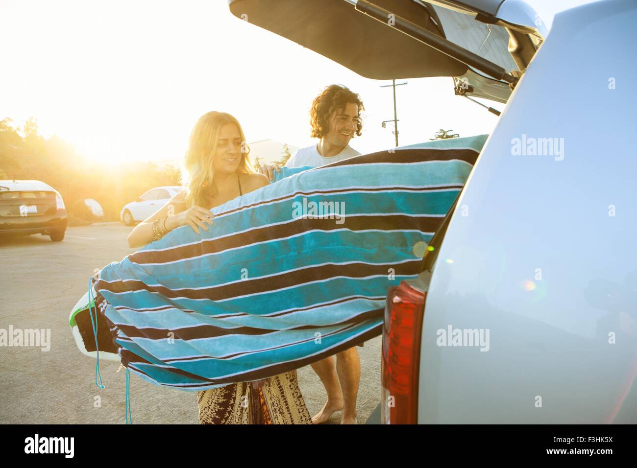 Giovane prendendo le tavole da surf dal bagagliaio della vettura Foto Stock