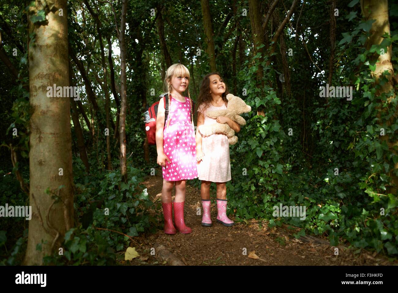 Due ragazze che trasportano orsacchiotto e zaino in foresta Foto Stock