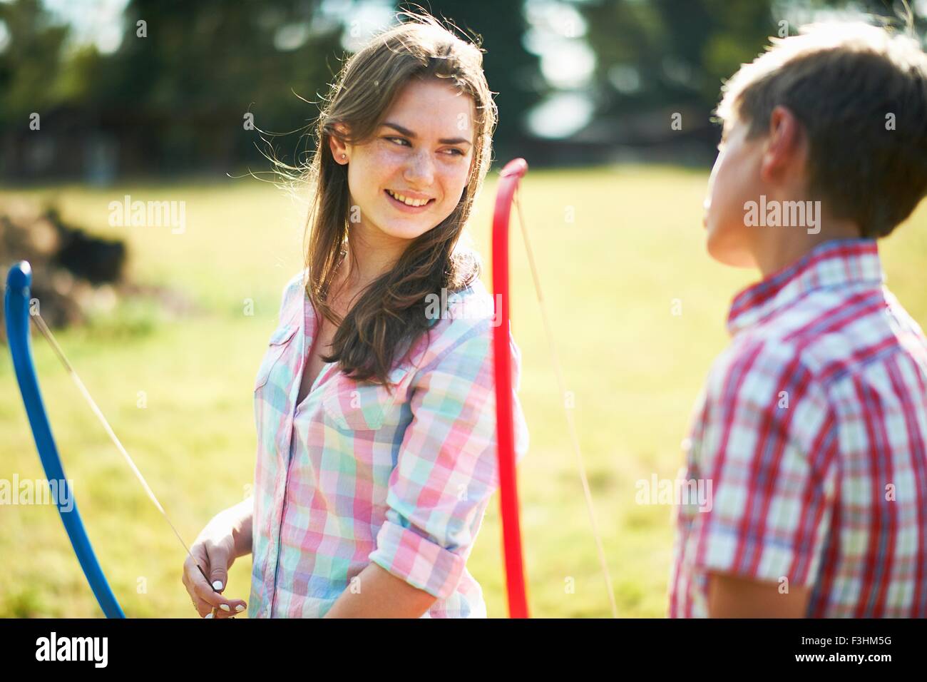 Ragazza adolescente parlando al fratello praticando tiro con l'arco Foto Stock