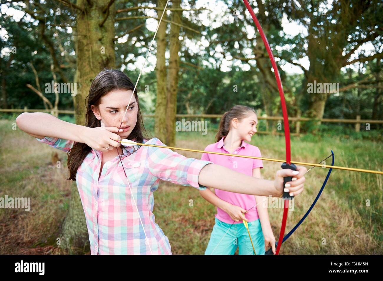 Ragazza e la sorella adolescente praticare il tiro con l'arco Foto Stock