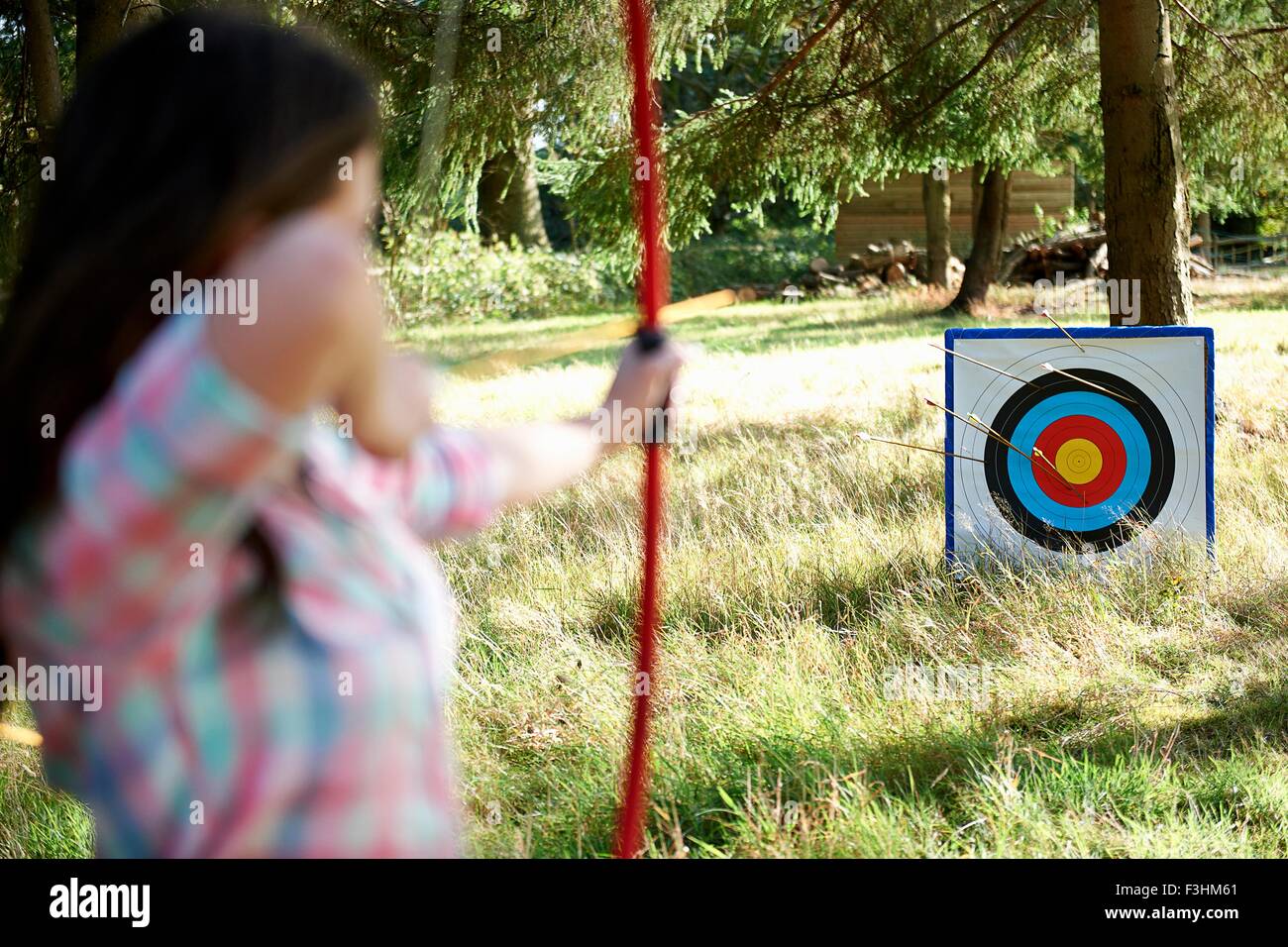 Vista posteriore della ragazza adolescente praticare il tiro con l'arco con obiettivo Foto Stock