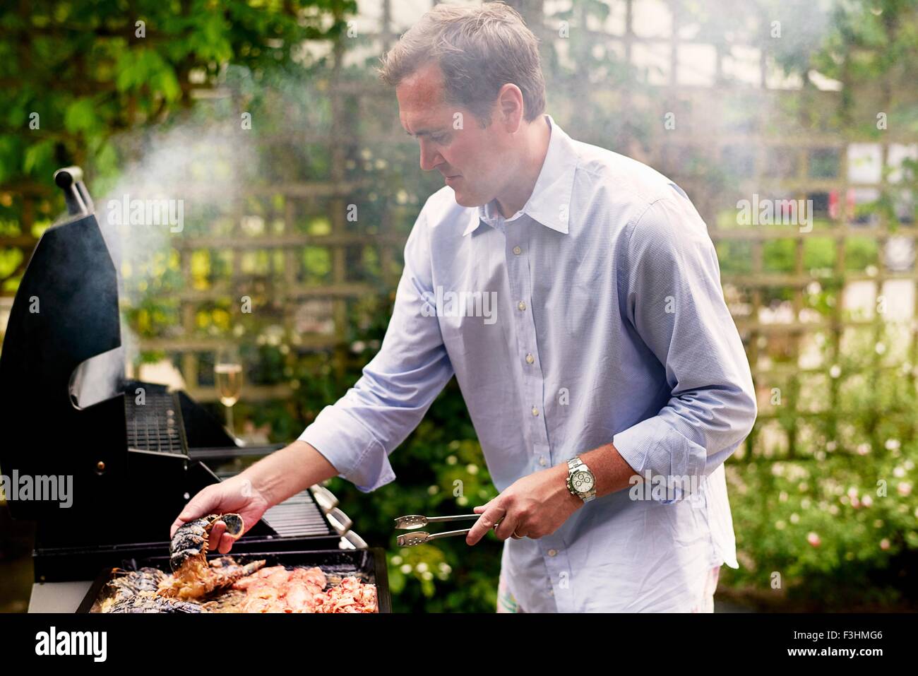 Uomo maturo cucinare pesce sul barbecue Foto Stock