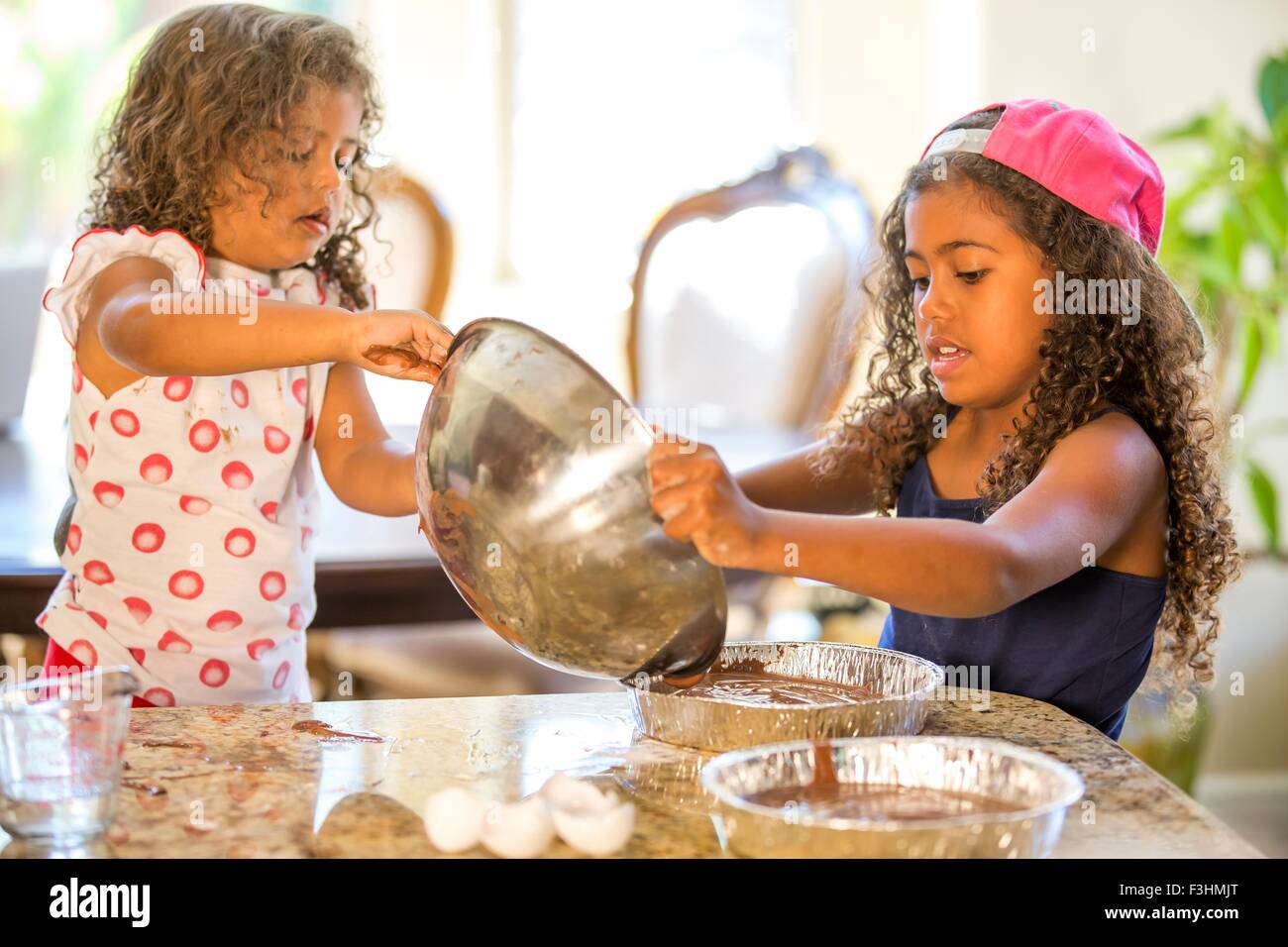 Ragazze versando cake mix da combinavano coppa in tortiere Foto Stock