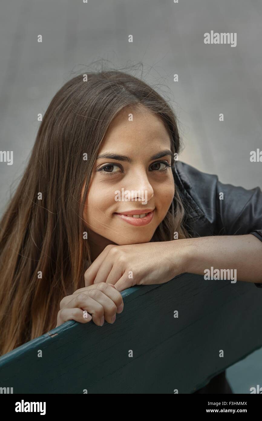 Angolo alto Ritratto di giovane donna mento sulla mano guardando sorridente della fotocamera Foto Stock