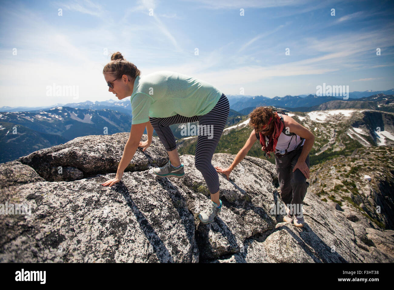 Un uomo e una donna scramble su roccia di granito su un crinale di montagna Foto Stock