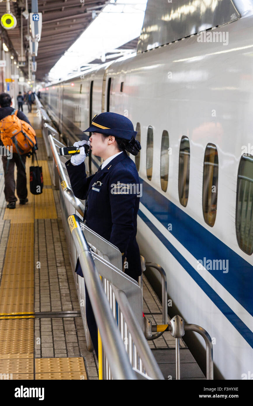 Stazione di Nagoya, conduttore di donna sulla piattaforma di clearing, shinkansen bullet train, a lasciare la stazione, rendendo annoucement per persone di tenersi a distanza. Foto Stock