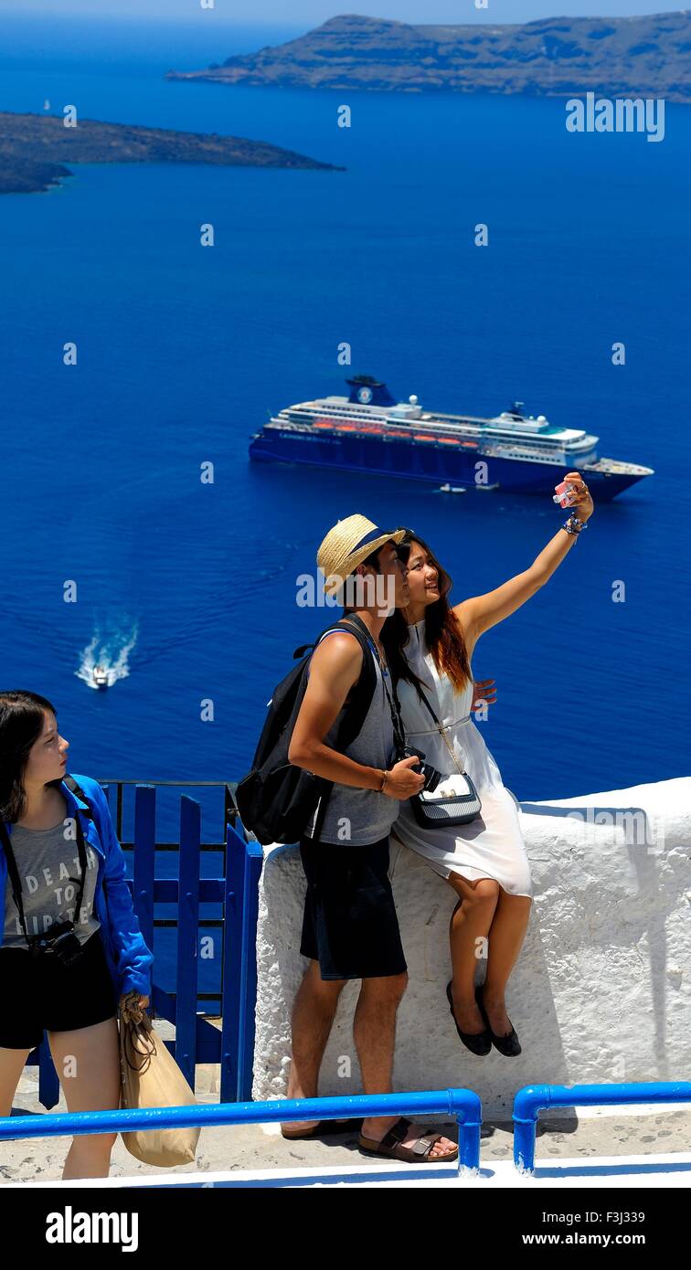 Turisti asiatici prendere una fotografia di se stessi con la caldera sullo sfondo Santorini Grecia Foto Stock