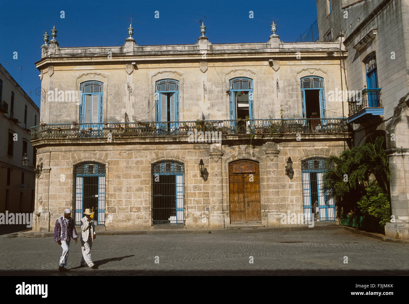 Cool-vestito cubani, uomini camminare attraverso la Plaza de la Catedral, Havana, Cuba Foto Stock