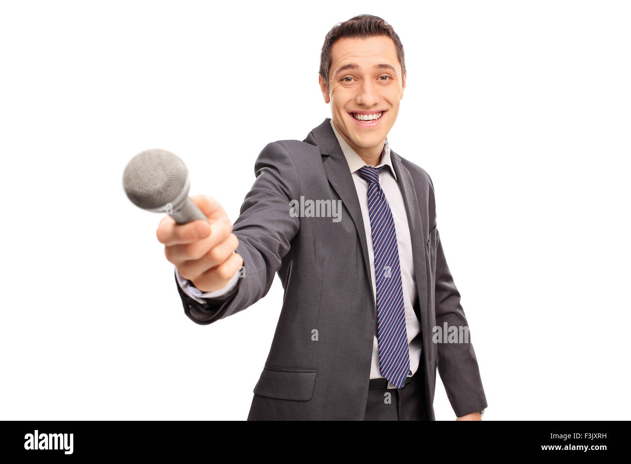 Allegro intervistatore in un abito grigio tenendo un microfono e guardando la telecamera isolata su sfondo bianco Foto Stock