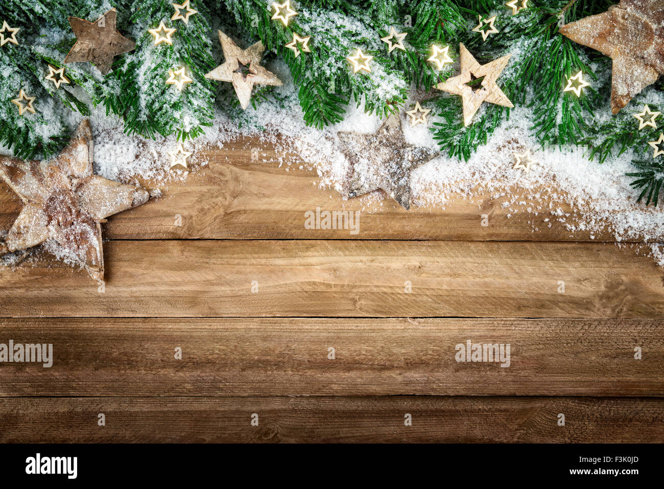 Sfondo di natale in legno naturale, in stile rustico, semplice ed elegante, con un bordo di rami di abete, stelle di legno e neve Foto Stock