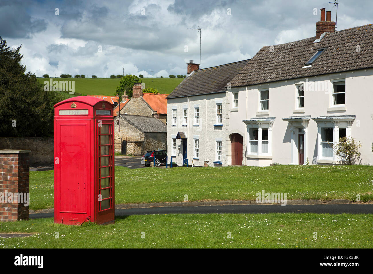 Regno Unito, Inghilterra, Yorkshire East Riding, Nord Newbold, casella Telefono e case intorno al villaggio verde Foto Stock