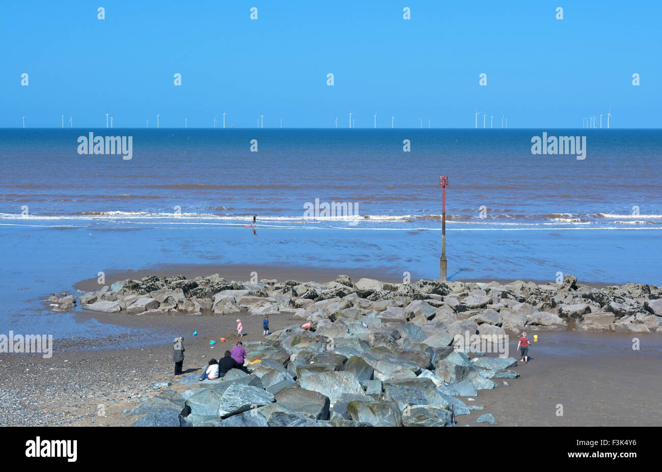 Famiglie sulla spiaggia di lungomare Withersea guardando fuori verso la Westermost ruvida per centrali eoliche offshore - Yorkshire, Inghilterra, Regno Unito Foto Stock