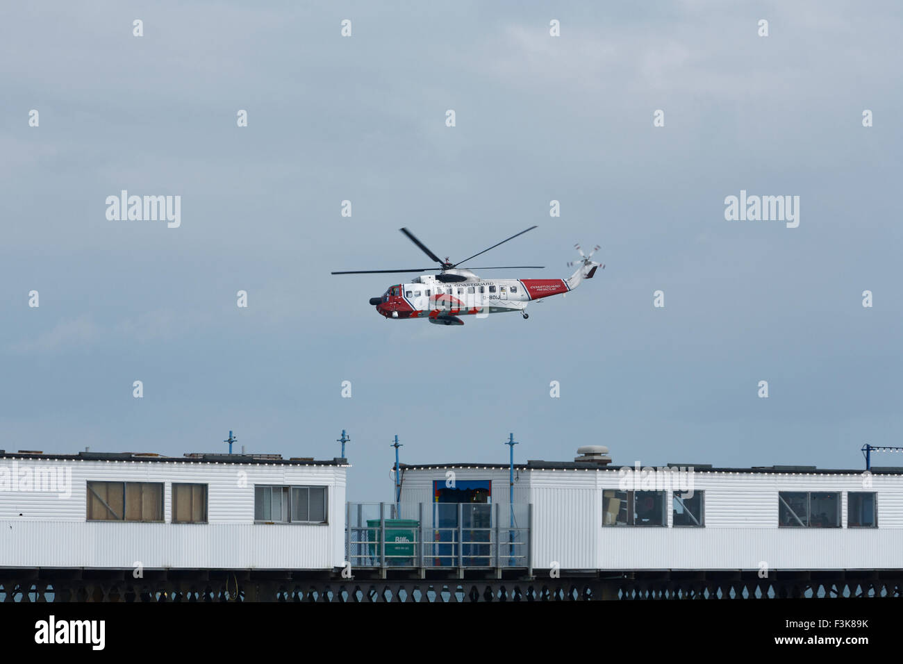 Edifici temporanei sul molo con H.M Coastguard caccia e salvataggio elicottero volare sullo sfondo nell'isola di wight, inghilterra regno unito Foto Stock