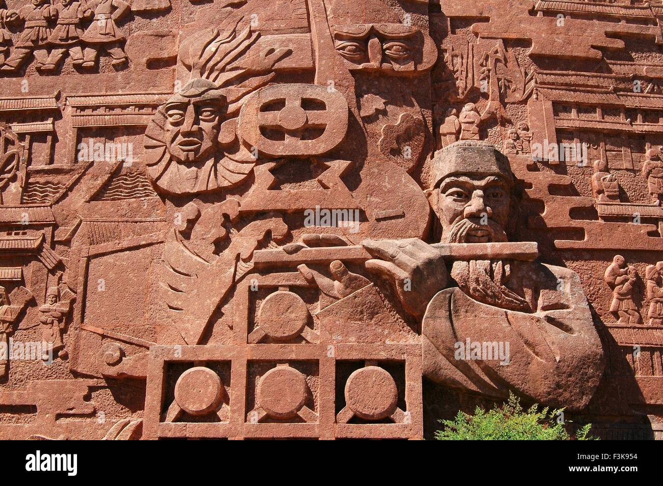 Lijiang, Cina: Bassorilievo parete scolpita in Si Feng Square raffigura un Naxi figure ed un musicista a doppia Stone Park Foto Stock