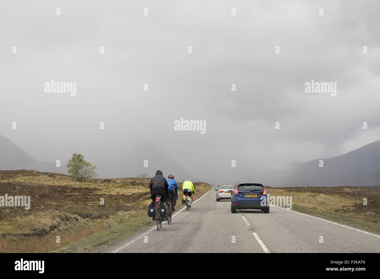 Vetture dando i ciclisti abbondanza di spazio come essi sorpassare sulla A82 strada attraverso Glencoe, Scotland, Regno Unito Foto Stock