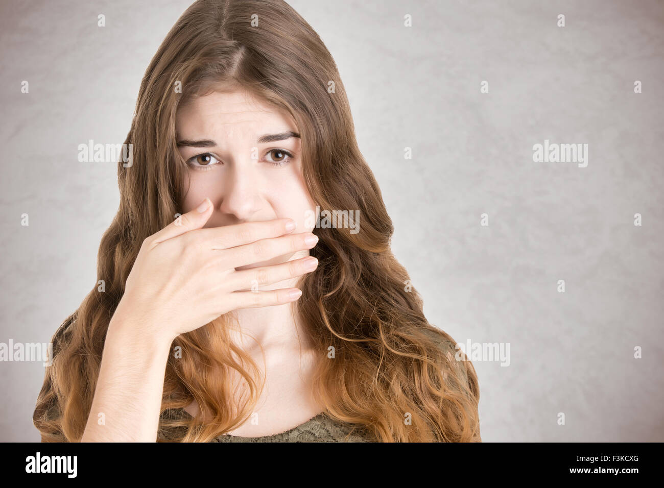 Copertura femmina la bocca con la mano, isolato in bianco Foto Stock