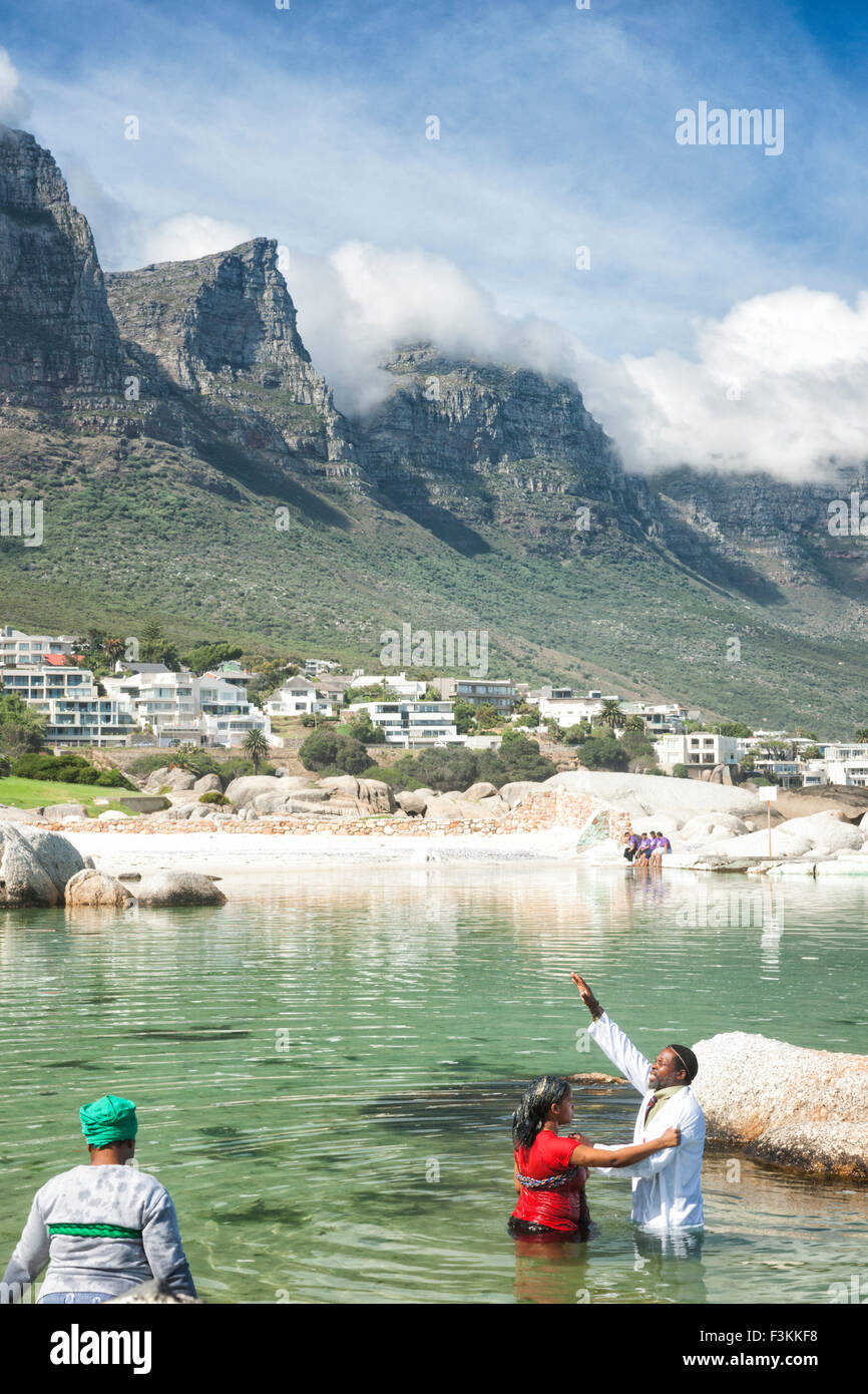 Sangoma guaritore di eseguire un battesimo con l'acqua nell'Oceano Atlantico, Table Mountain dodici Apostoli in background, Camp's Bay, Cap Foto Stock