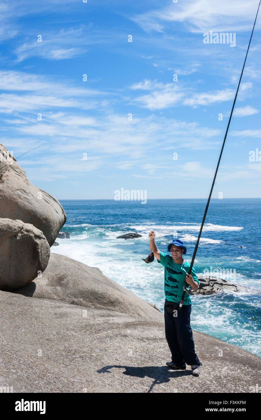 Ragazzo detiene un pesce appena pescato a Llandudno cove beach segnata da massi di granito, Oceano Atlantico, tra il Campeggio Baia e ho Foto Stock