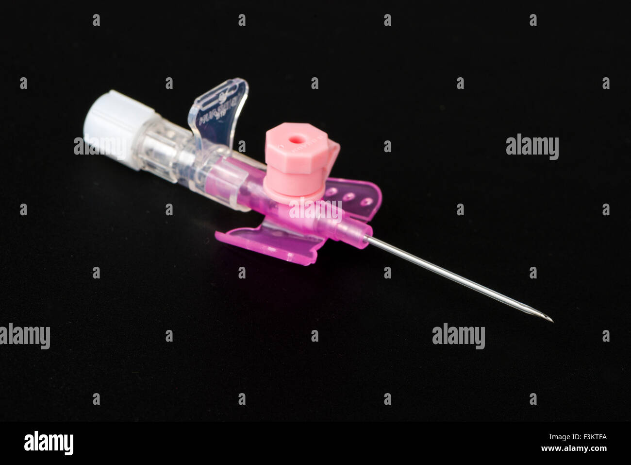 Una sicurezza rosa catetere iv con porta di iniezione per uso medico, visualizzato su una tavola nera Foto Stock